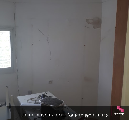 קיר עם סדקים וכתמים, שולחן עם חפצים